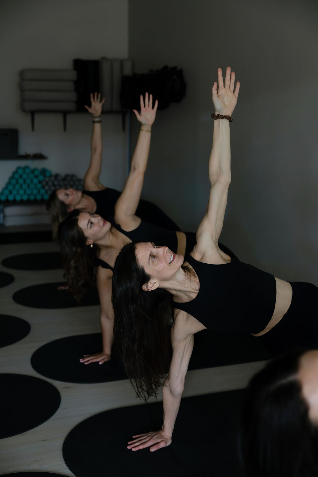 Alisa leading a yoga class in side-plank pose with two students